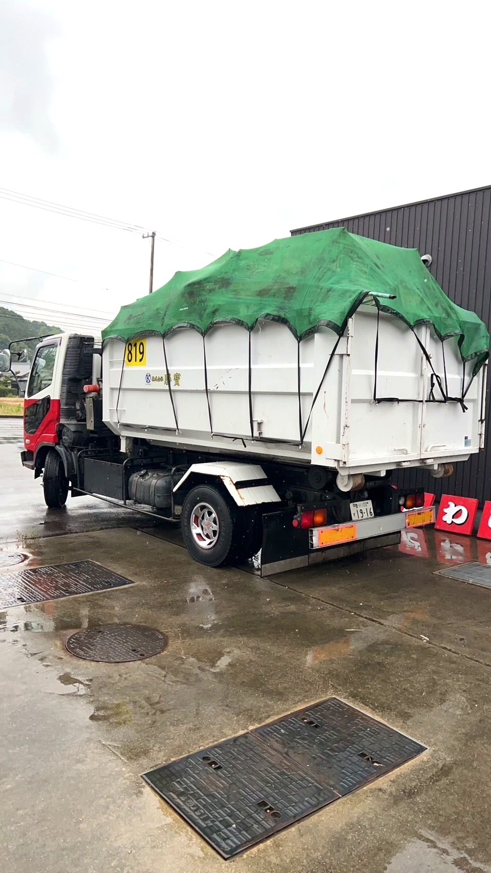 雨の日にシートを掛けて安全運搬する勝寳のアームロール車